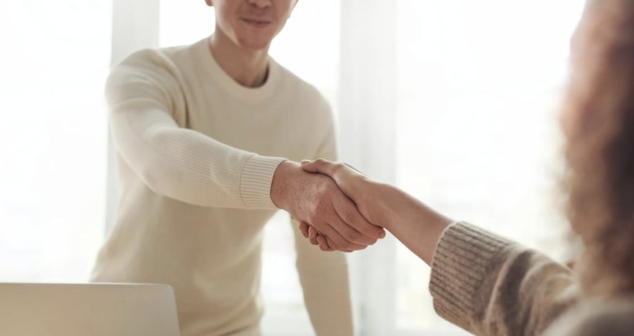A close-up shot of two individuals shaking hands, symbolizing agreement or greeting.