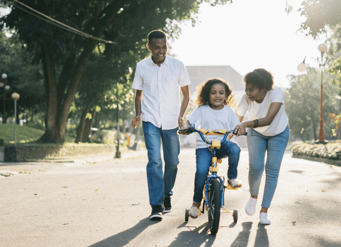 Family walking together outdoors as a child rides a bike, symbolizing unity and support in everyday life