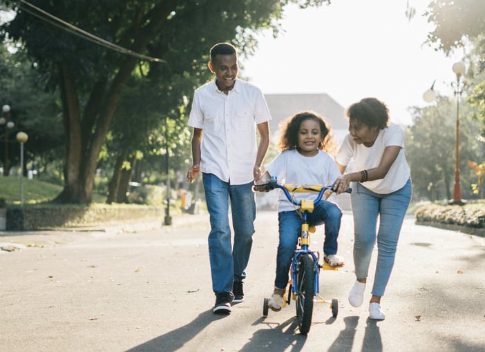 Family walking together outdoors as a child rides a bike, symbolizing unity and support in everyday life