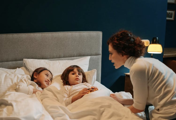 Nanny tucking two young children into bed, creating a warm and caring bedtime environment
