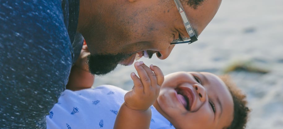 father laughing with his baby, swooping him upside-down